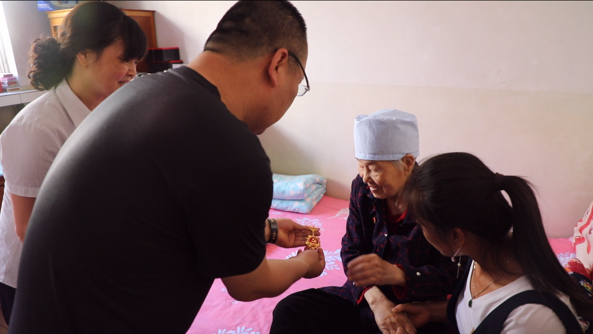 西峰區(qū)炮臺巷社區(qū)黨總支書記張永治為李秀芳頒發(fā)紀念章。梁博睿/攝